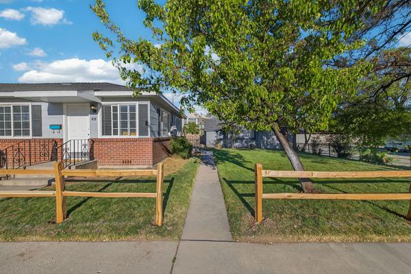 Concrete walk from the sidewalk to the front door, through the split-rail fence, with a tree shading the lawn