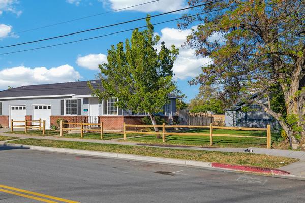 The duplex from across the street, with its two white garage doors, the split-rail fence and mature trees