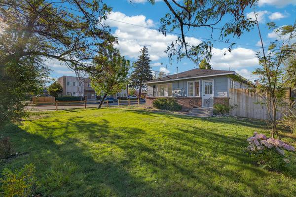 Wide lawn beside the duplex under mature trees, with a wooden privacy fence
