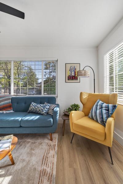 Mustard armchair beside the teal sofa, with a floor lamp and a framed vintage Reno print