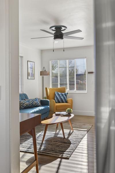 The living room seen through a doorway: armchair, sofa and oval coffee table in afternoon light