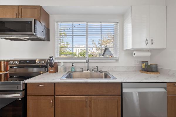 Sink under a window, with the dishwasher to the right and the range to the left