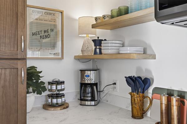 Coffee corner with a drip coffee maker, a spice rack and open shelves of plates and glasses