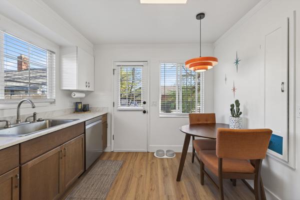 Dining nook with a round table and two orange chairs by the back door, with the sink and dishwasher along the wall