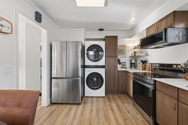 Stainless refrigerator and a stacked washer and dryer at the end of the kitchen run
