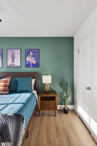 Bedside with a walnut nightstand, a potted cactus and a white door