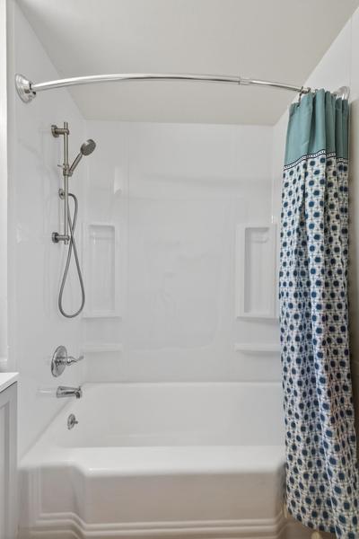 Tub and shower with a curved curtain rod and a handheld shower head