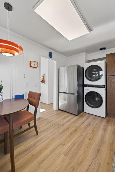 Full-size stacked washer and dryer next to the refrigerator, beside the dining table